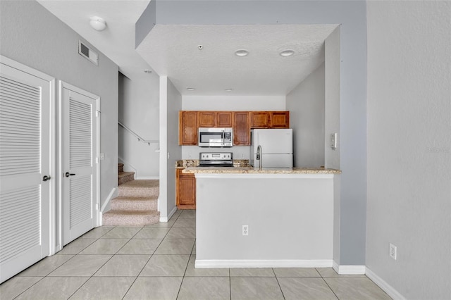 kitchen with stainless steel appliances, light tile patterned floors, and a textured ceiling