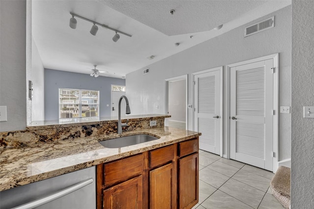 kitchen with sink, light stone counters, light tile patterned floors, stainless steel dishwasher, and ceiling fan