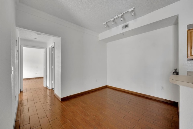 spare room with hardwood / wood-style flooring, rail lighting, and a textured ceiling