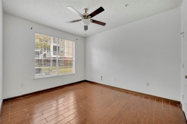 empty room with ceiling fan, a textured ceiling, and light wood-type flooring