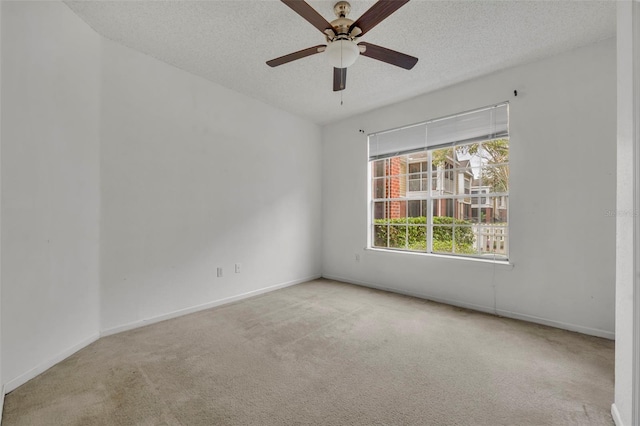 spare room featuring ceiling fan, light colored carpet, and a textured ceiling