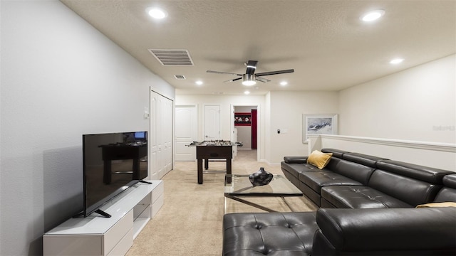 carpeted living room with a textured ceiling and ceiling fan