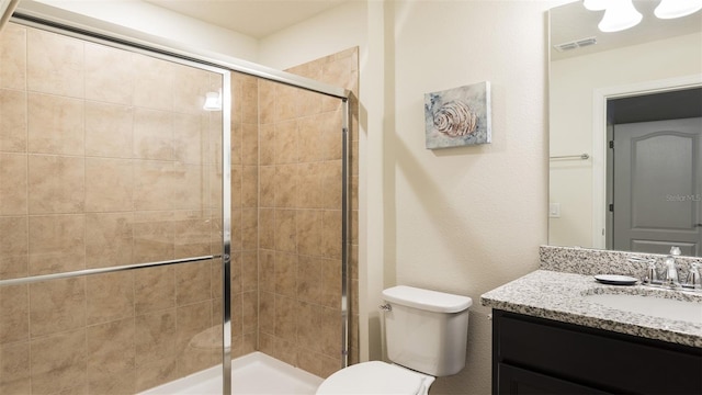 bathroom with toilet, vanity, and a shower with shower door