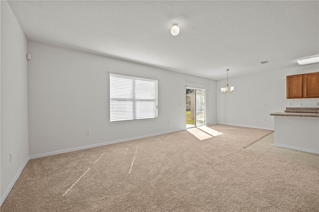 unfurnished living room with light carpet, a textured ceiling, and an inviting chandelier