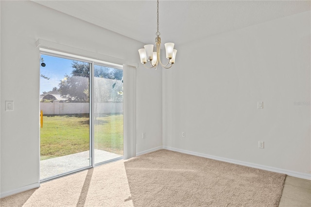 carpeted spare room featuring an inviting chandelier