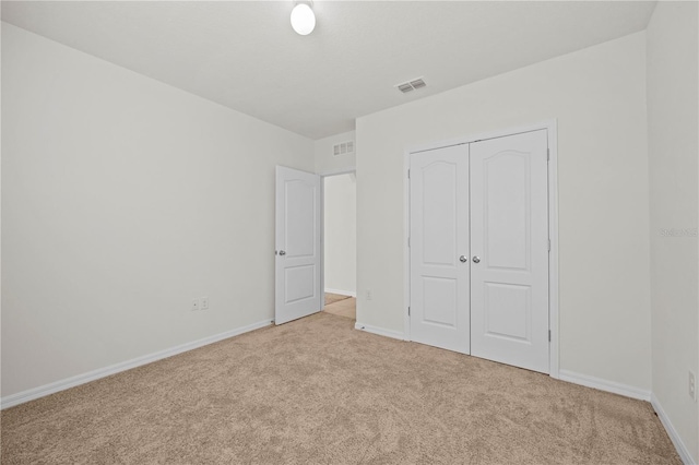 unfurnished bedroom featuring light colored carpet and a closet