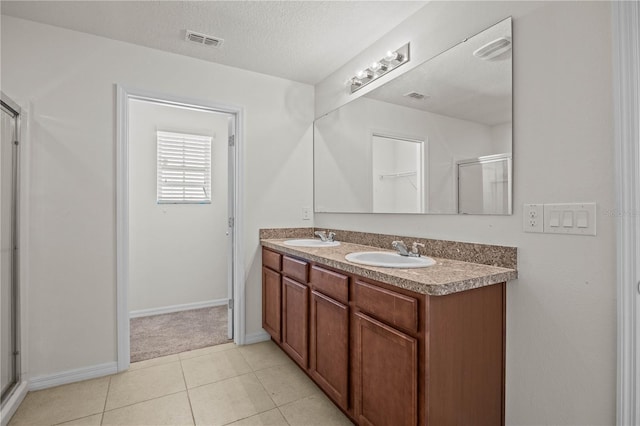 bathroom featuring vanity, an enclosed shower, tile patterned flooring, and a textured ceiling