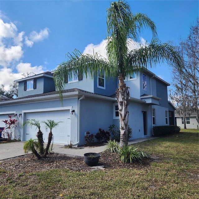 view of front of property with decorative driveway, a garage, a front yard, and stucco siding