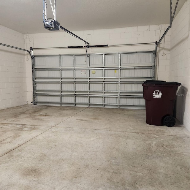 garage featuring concrete block wall and a garage door opener