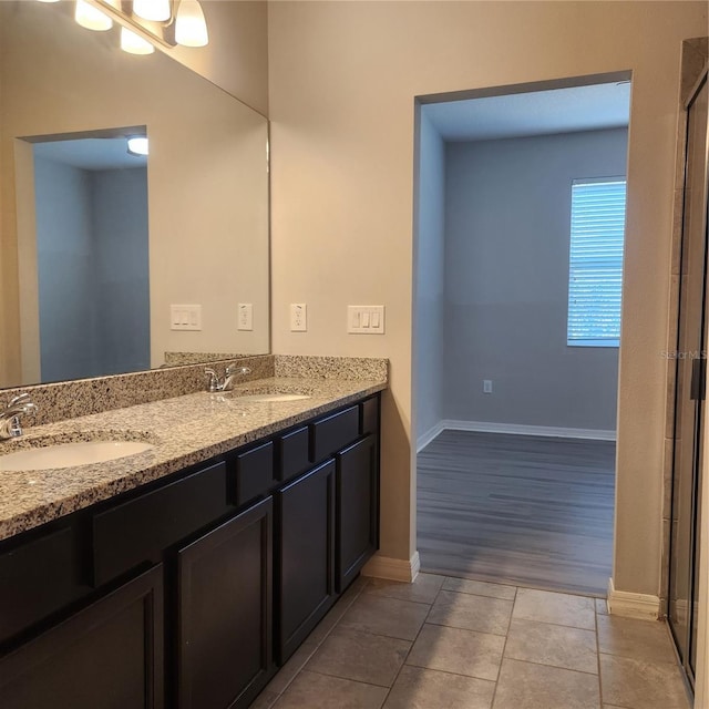 bathroom featuring a sink, baseboards, double vanity, and tile patterned flooring