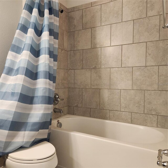 bathroom featuring toilet and shower / bathtub combination with curtain