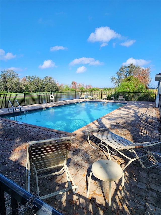 pool with a patio and fence