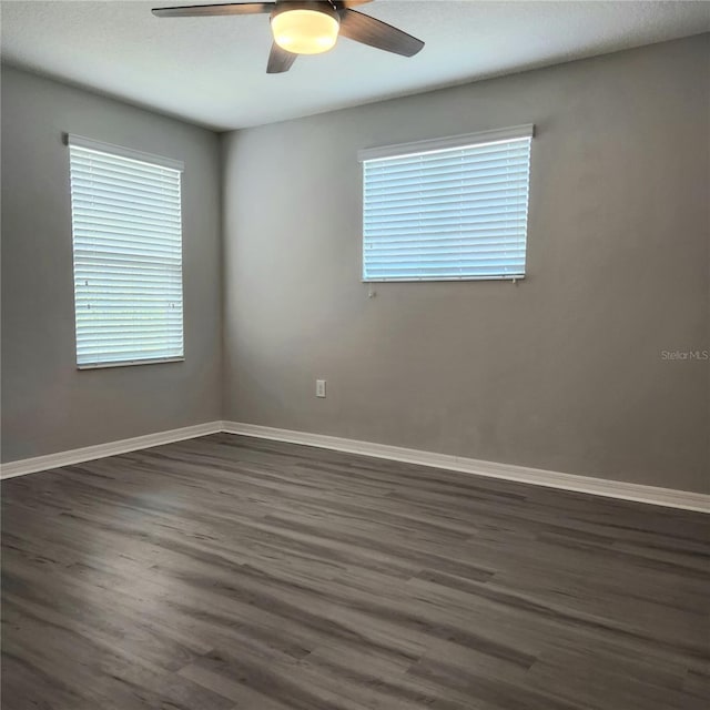 unfurnished room featuring ceiling fan, baseboards, plenty of natural light, and dark wood-style floors