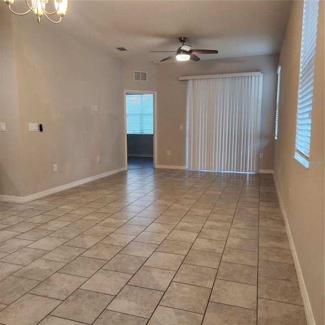 spare room featuring light tile patterned floors, visible vents, ceiling fan with notable chandelier, and baseboards