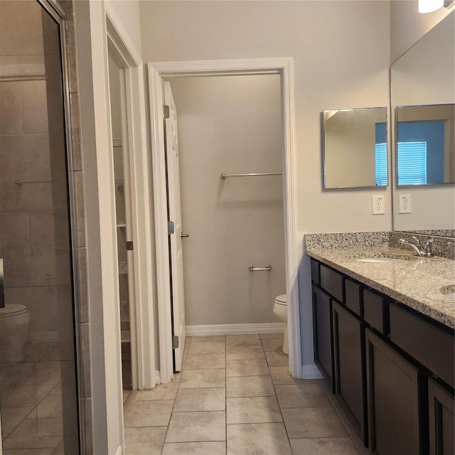 full bathroom featuring a walk in closet, toilet, a stall shower, a sink, and baseboards