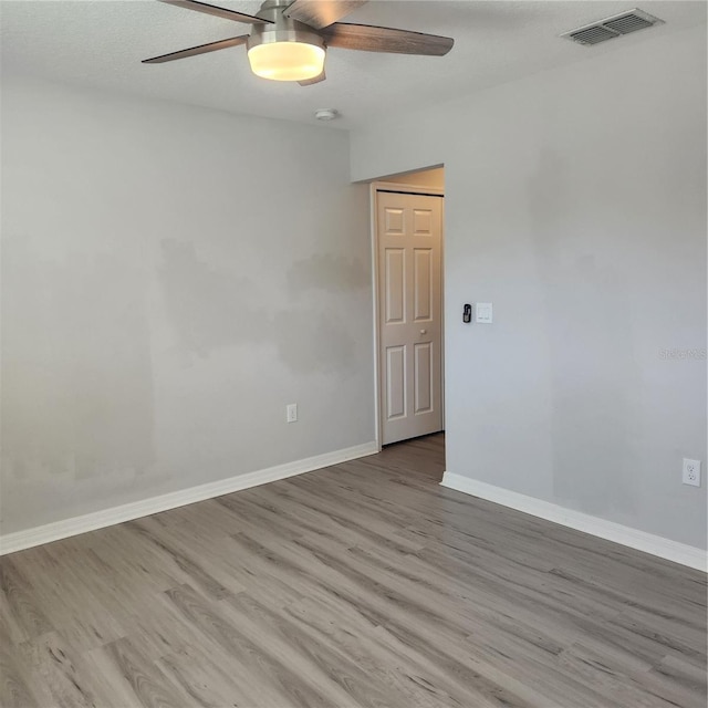 unfurnished room featuring light wood finished floors, visible vents, baseboards, and a ceiling fan