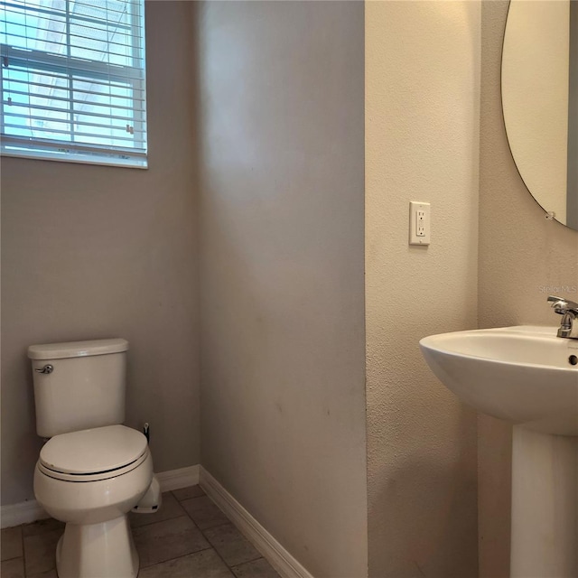 bathroom with tile patterned floors, baseboards, toilet, and a sink