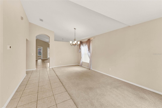 tiled empty room featuring a healthy amount of sunlight and a notable chandelier