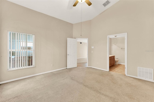 unfurnished bedroom with ceiling fan, high vaulted ceiling, light colored carpet, and ensuite bathroom