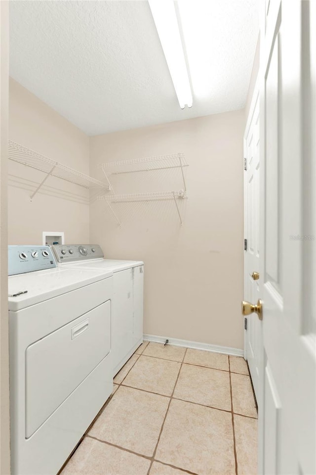 laundry room with light tile patterned flooring, washing machine and dryer, and a textured ceiling