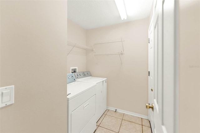 clothes washing area featuring light tile patterned flooring and separate washer and dryer