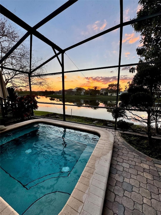 pool at dusk with a water view and glass enclosure