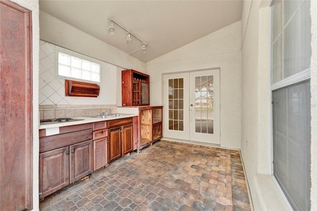 bathroom featuring french doors, sink, backsplash, vaulted ceiling, and track lighting