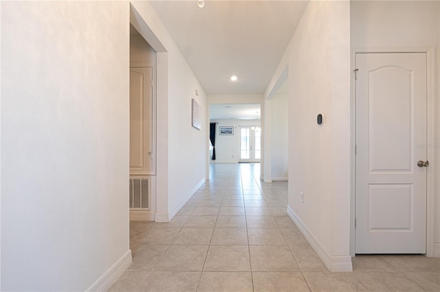 corridor featuring light tile patterned floors, baseboards, and visible vents