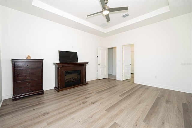 unfurnished living room featuring a raised ceiling, visible vents, a fireplace, and light wood-style flooring