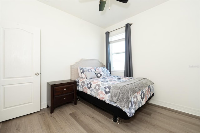 bedroom with a ceiling fan, baseboards, and light wood finished floors