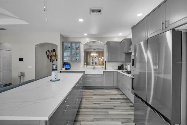 kitchen featuring sink, a center island, appliances with stainless steel finishes, gray cabinets, and light stone countertops