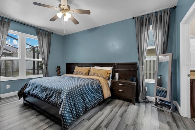 bedroom with ceiling fan, multiple windows, and light wood-type flooring