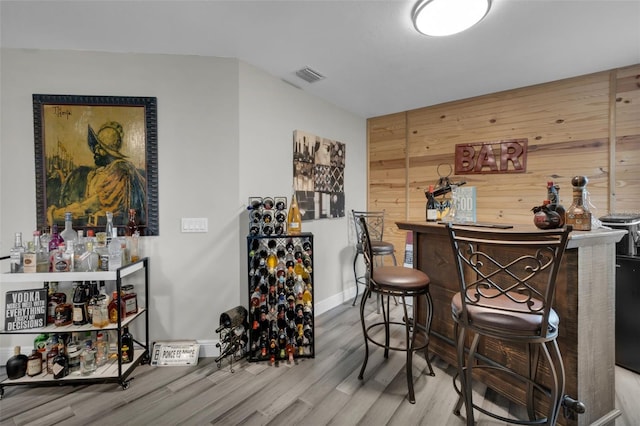 bar with hardwood / wood-style flooring and wooden walls