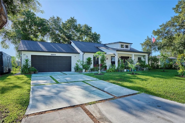 view of front of house with a garage, driveway, a front lawn, and stucco siding