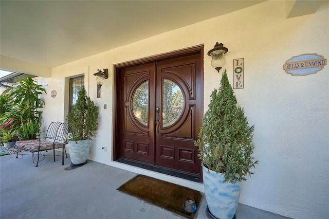 property entrance with covered porch and stucco siding