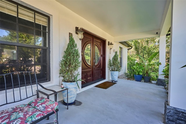 property entrance with a porch and stucco siding