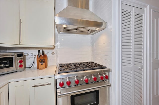 kitchen with luxury range, a toaster, decorative backsplash, white cabinets, and extractor fan