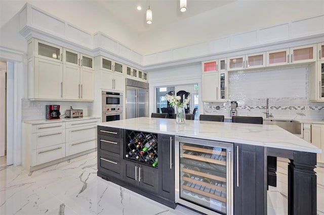 kitchen with wine cooler, appliances with stainless steel finishes, a sink, marble finish floor, and backsplash