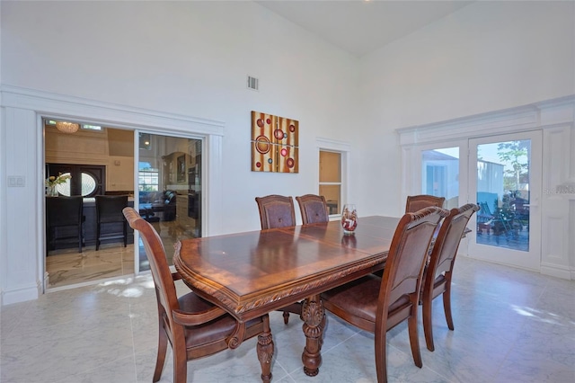 dining room featuring marble finish floor, french doors, a high ceiling, and visible vents