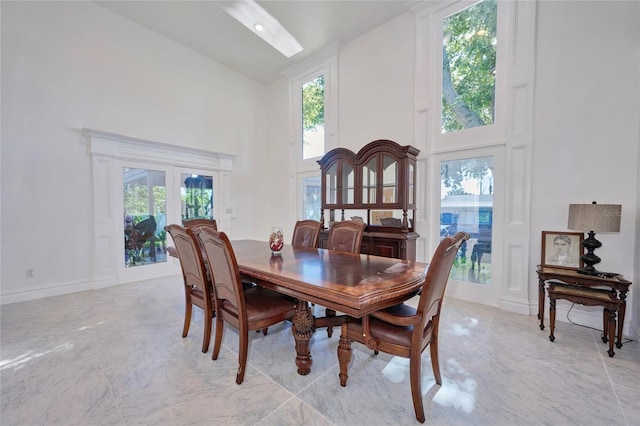 dining area featuring marble finish floor, high vaulted ceiling, and a wealth of natural light