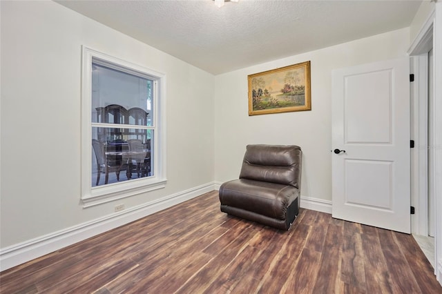 sitting room featuring baseboards, dark wood finished floors, and a textured ceiling