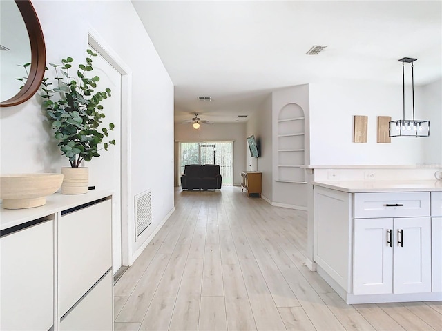 corridor with visible vents, baseboards, and light wood-style floors