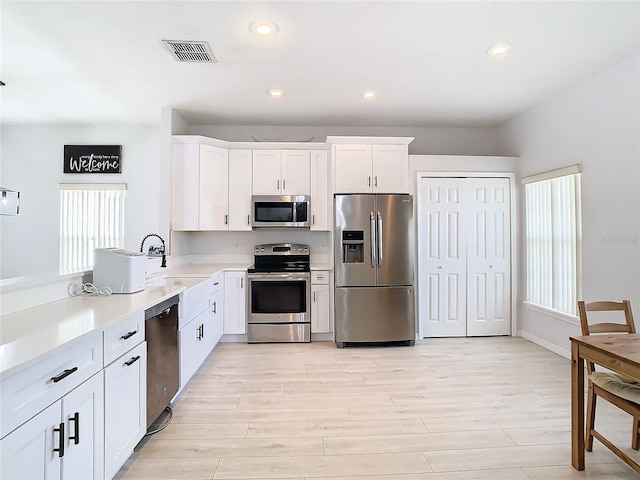 kitchen featuring visible vents, light wood finished floors, a sink, stainless steel appliances, and light countertops