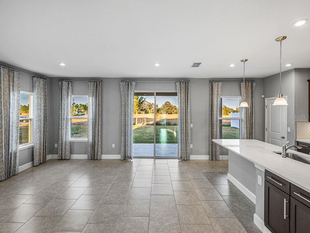 interior space with sink, light tile patterned floors, dark brown cabinetry, and decorative light fixtures