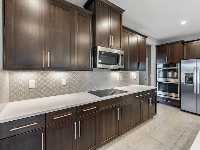 kitchen featuring light tile patterned floors, decorative backsplash, dark brown cabinets, and appliances with stainless steel finishes