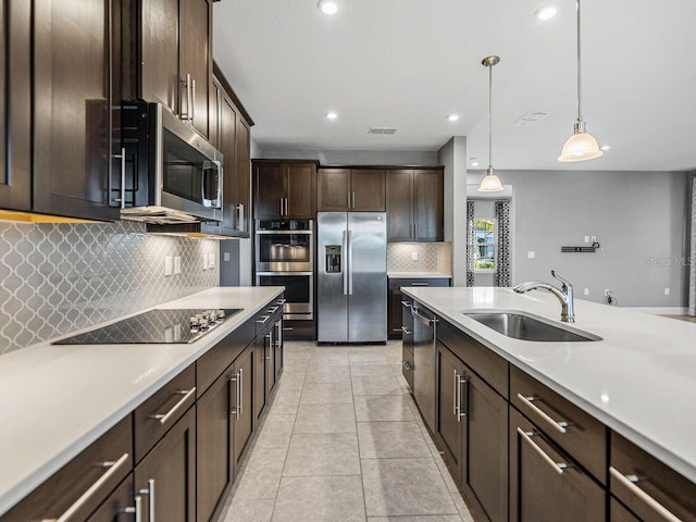 kitchen featuring pendant lighting, dark brown cabinetry, sink, and black appliances