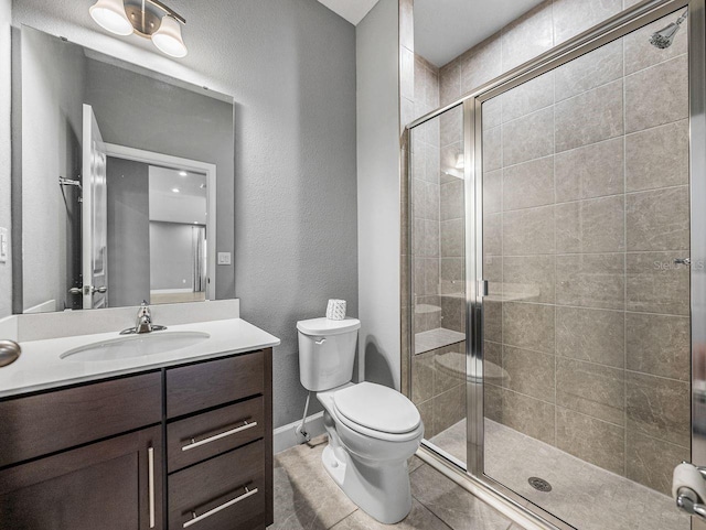 bathroom featuring tile patterned flooring, vanity, walk in shower, and toilet