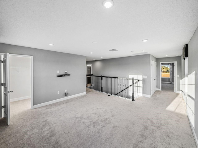 empty room with light colored carpet and a textured ceiling