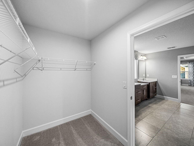 walk in closet with sink and light colored carpet