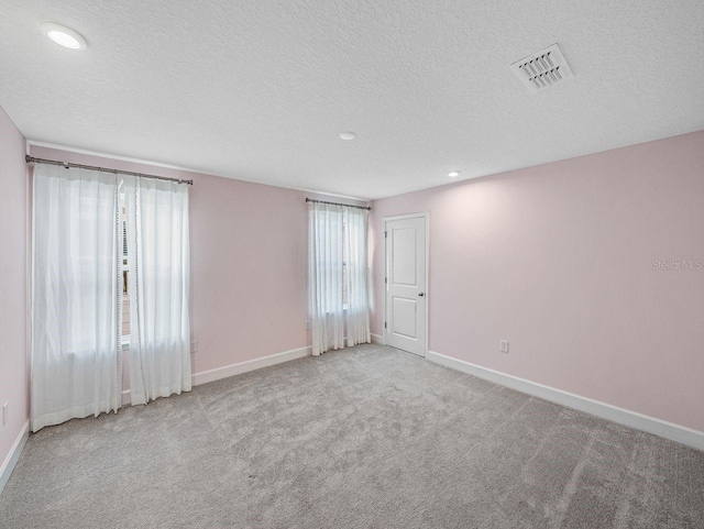 empty room with light carpet and a textured ceiling